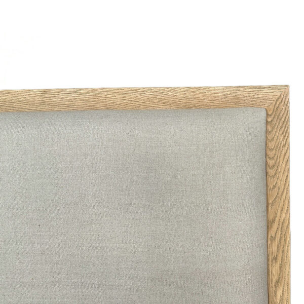 Close-up of luxury king bedroom headboard with light grey linen fabric and a natural wood frame, focusing on the upper-right corner.