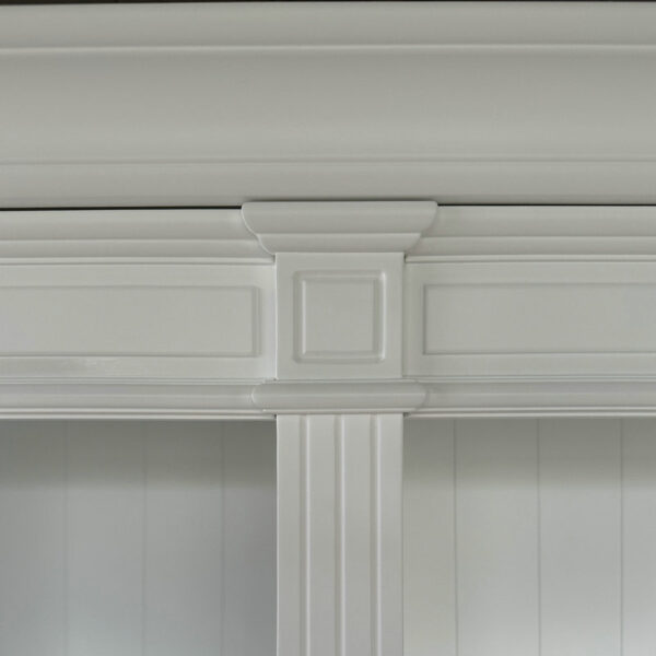 Close-up of a detailed white door frame with decorative molding, next to sophisticated wooden white wall bookshelves.