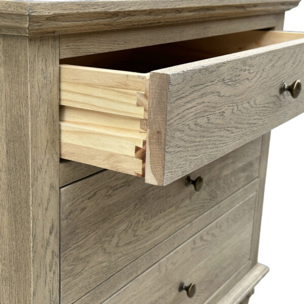 A close-up of a solid oak dresser with three drawers, the top partially open to show dovetail joinery, featuring metal knobs and a rustic finish.