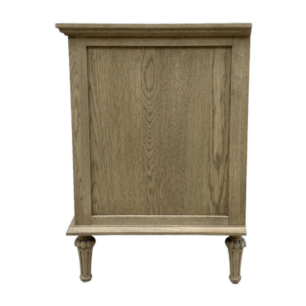 A 3-drawer solid oak nightstand with a paneled front and short legs, boasting a light finish perfect for adding rustic charm to any bedroom.