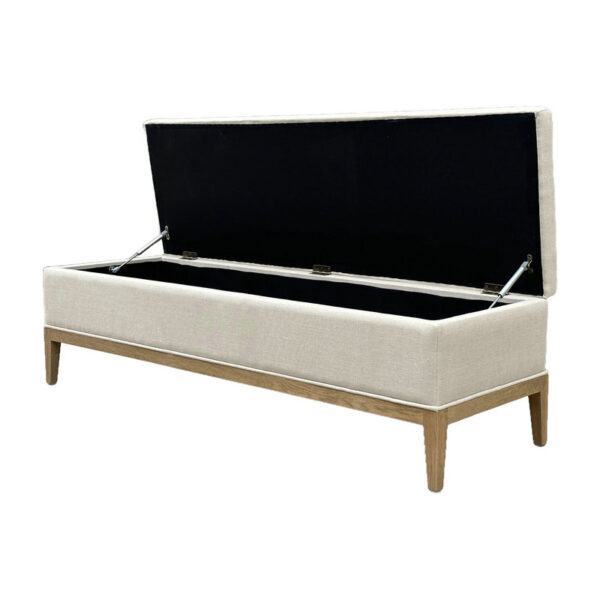 The beige linen ottoman has wooden legs, opens to reveal black storage inside, and serves as both a footrest and bench.