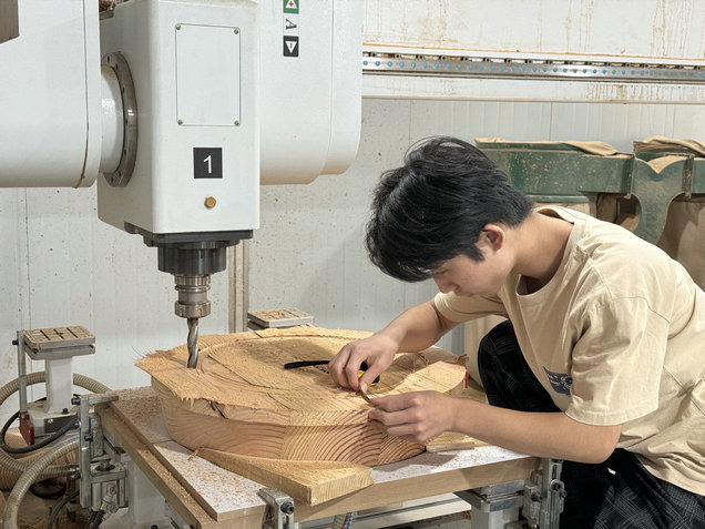 A person using a CNC machine to measure wood in a workshop.