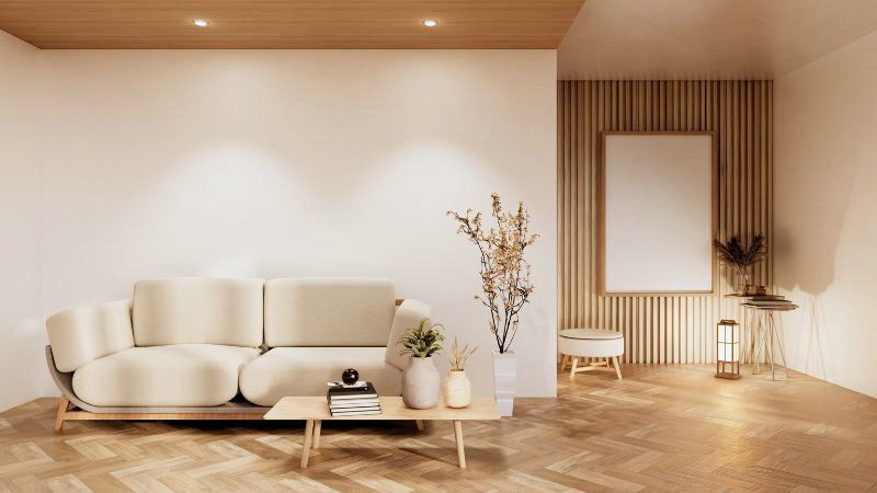 A minimalist living room features a beige sofa, Hoolnn's bouclé furniture, a wooden coffee table, books, plants, and light wood flooring.