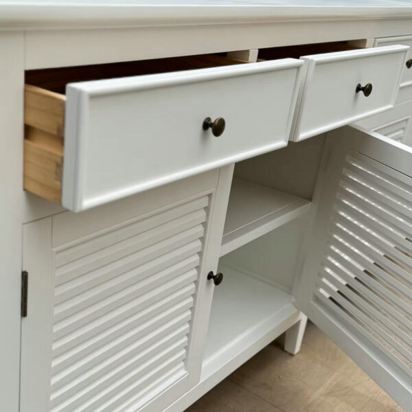 The Hamptons Luxurious Style White Birch Sideboard has slatted doors, two knobbed drawers, and spacious shelves inside.