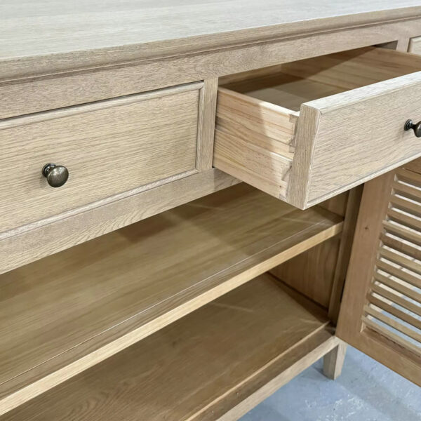 Wooden cabinet with two drawers (one open), two open shelves, slatted doors, and a natural finish.