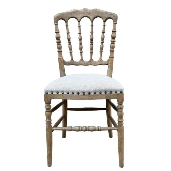 Wooden chair with spindle back, upholstered seat, and nailhead trim, shown from the front on a plain background.