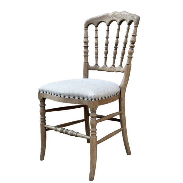 Wooden dining chair with carved backrest, spindles, and a light upholstered cushioned seat.