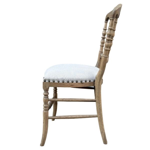 Wooden dining chair with light upholstered seat, turned legs, and curved backrest in side profile view.