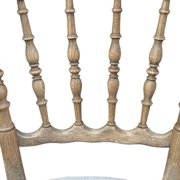 Close-up of a wooden chair's upper backrest with vertical spindles and curved support, isolated on white background.