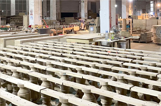 Kokapstrādes rūpnīcu rotā nepabeigti koka balustrāti, fonā — darbagaldi un iekārtas.