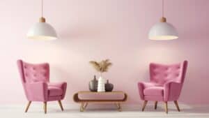 Two pink armchairs face each other in a pastel room with a wood coffee table, vases, pampas grass, and white pendant lights.