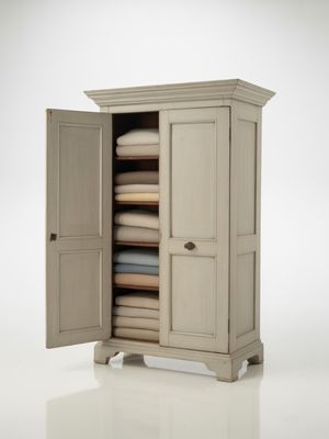Elegant antique white wooden wardrobe showcasing spacious interior with neatly folded plush towels, ideal for stylish bedroom storage solutions.